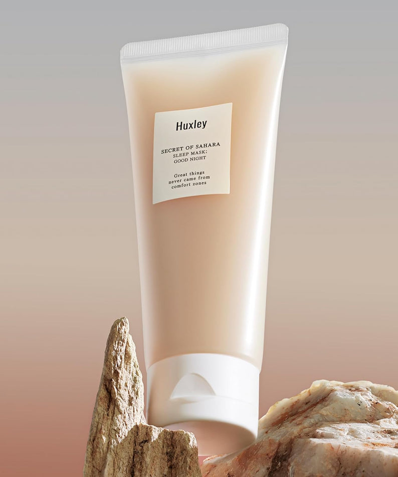 HUXLEY Sleep Mask Good Night pose sur des rochers, soin de nuit pour une peau éclatante et hydratée. Tube de masque visage HUXLEY.