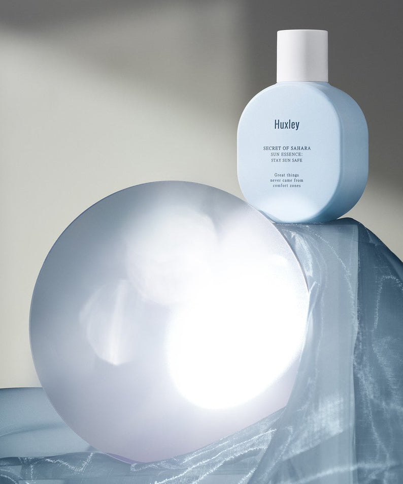HUXLEY Sun Essence Stay Sun Safe, produit solaire moderne sur fond bleu élégant, protection optimale contre le soleil.