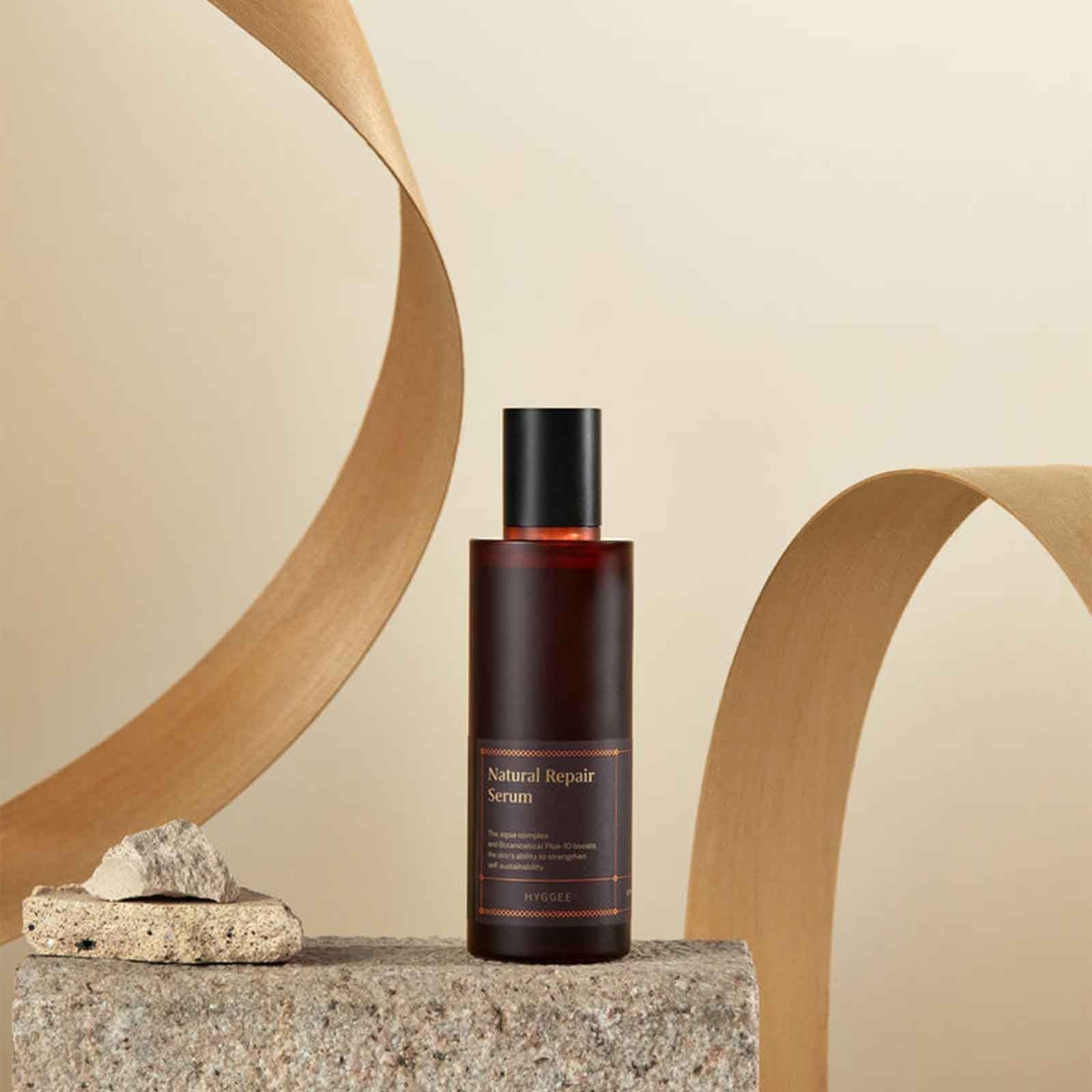 HYGGEE Natural Repair Serum 120ml de HYGGEE, flacon sur pierre avec décor bois beige, contexte beauté naturel