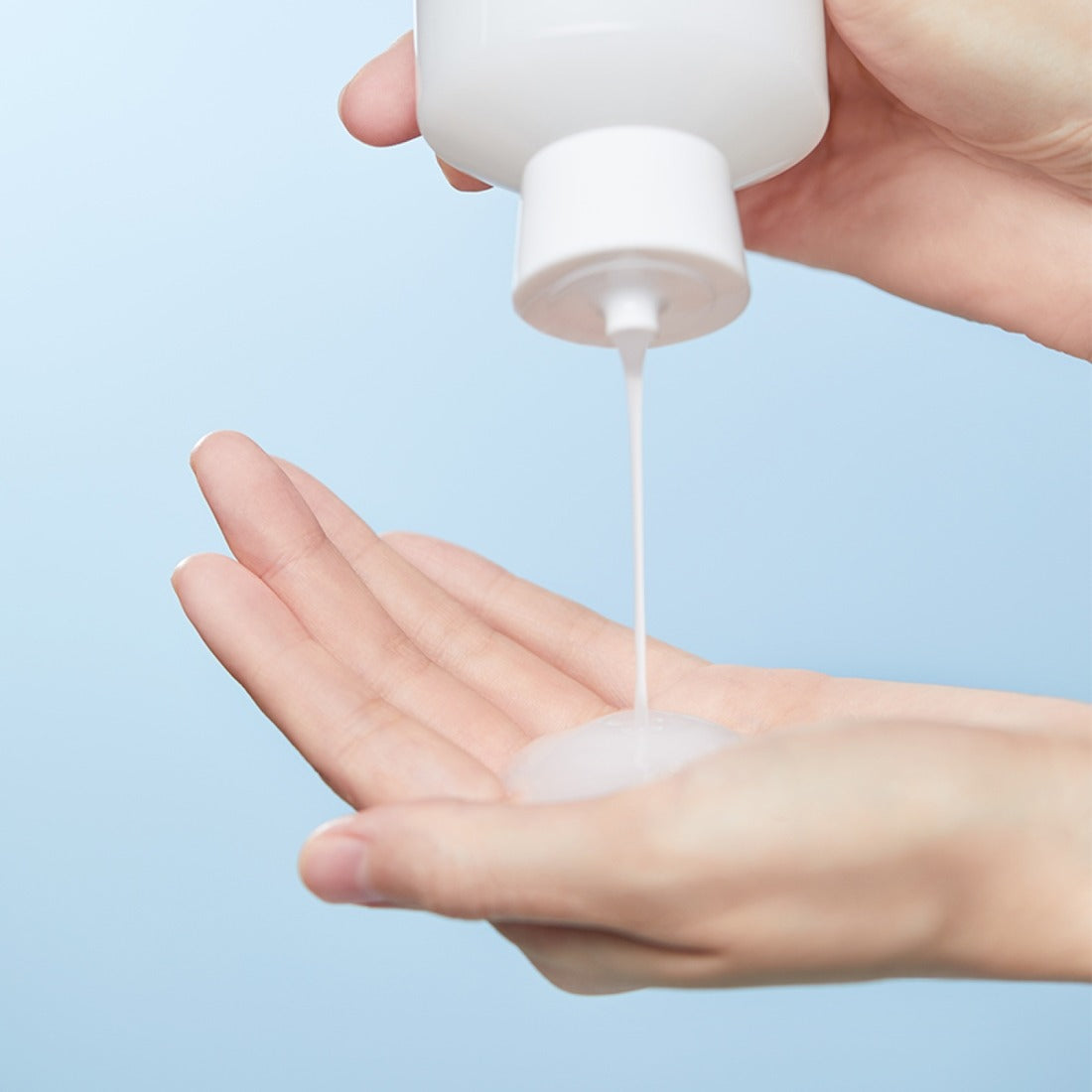 ILLIYOON Ceramide Ato Moisturizing Skin 250ml : tube crème appliquée sur mains, fond bleu, mise en scène peau hydratée