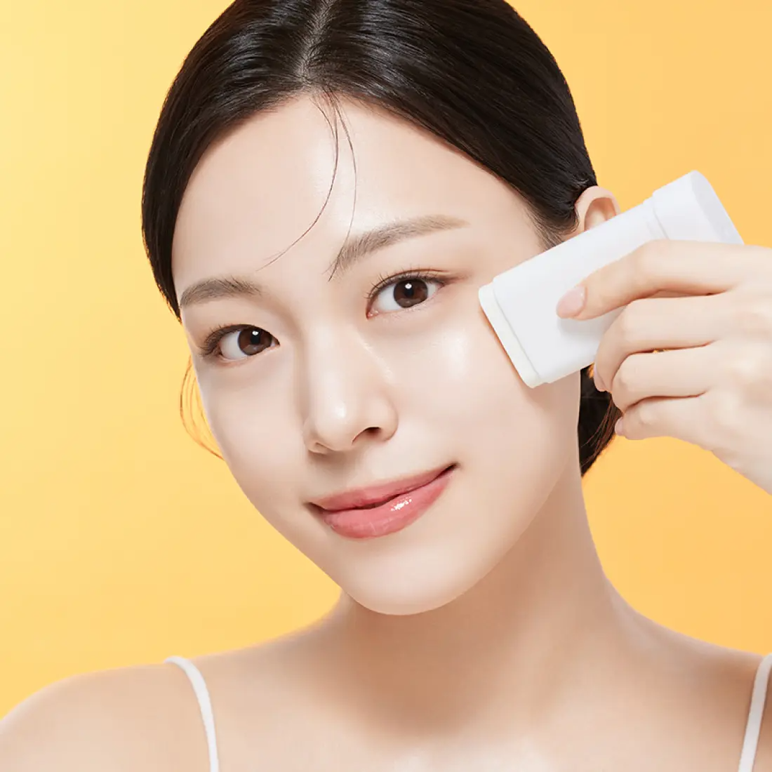 ILLIYOON Daily Weaponless Sun Stick 20g de la marque ILLIYOON sur le visage, application d’un stick solaire, fond jaune.