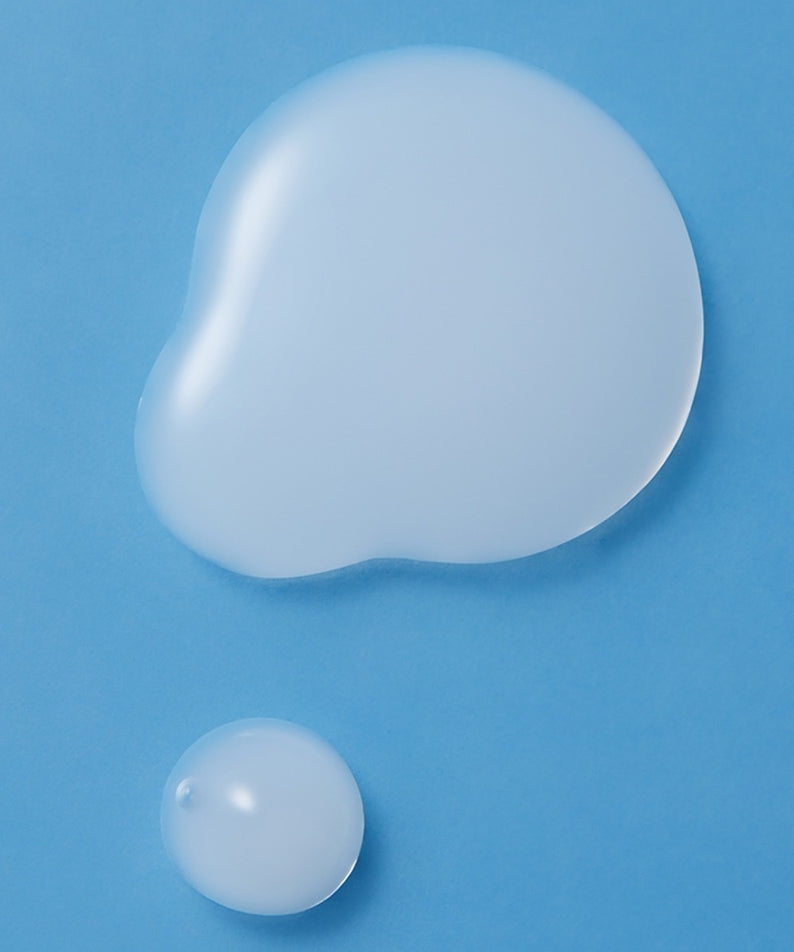 Texture de ILLIYOON Ceramide Ato Moisturizing Skin 250ml sur fond bleu, deux gouttes de produit hydratant.