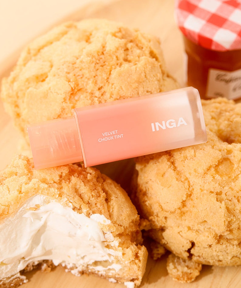 Rouge à lèvres INGA Velvet Stain posé sur des choux à la crème, scène de pâtisserie.