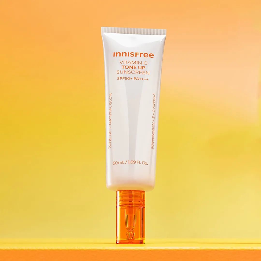 INNISFREE Vita C Spot Tone Up Sunscreen SPF50+/PA++++ 50ml, tube crème solaire sur fond jaune ensoleillé.
