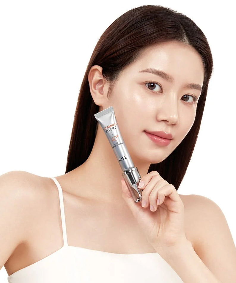 Jeune femme sur fond clair tenant le IOPE Vitamin C Expert 40% Mask Concentrate 15g de la marque IOPE