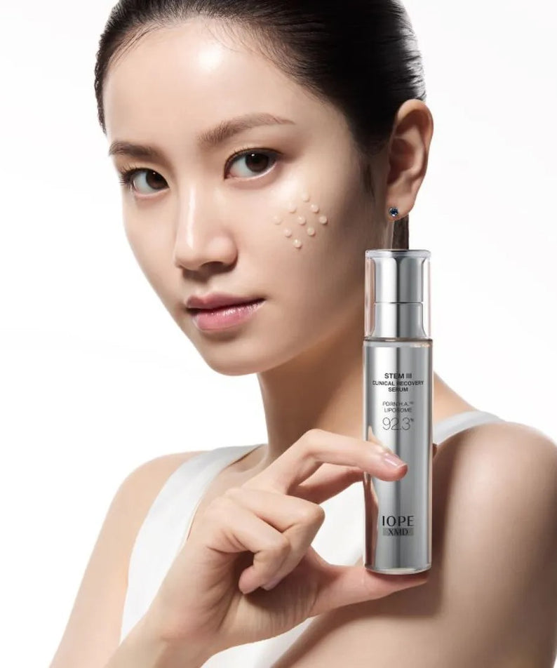 IOPE XMD Stem3 Clinic Recoery Serum 50ml : sérum présenté sur une femme, flacon sur fond clair, marque IOPE.