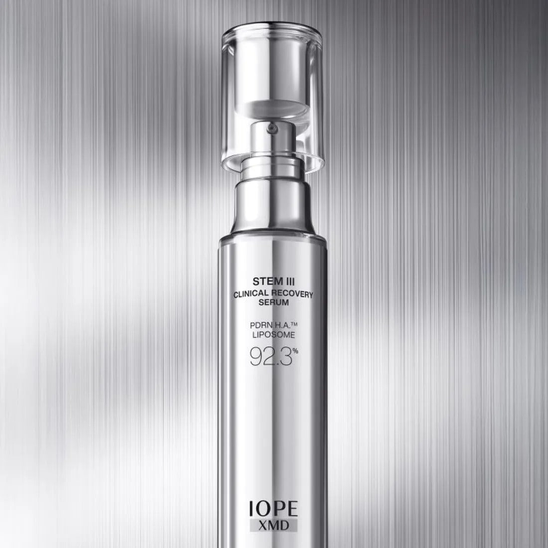IOPE XMD Stem3 Clinic Recoery Serum 50ml, flacon argenté sur fond rayé, image produit de marque IOPE.