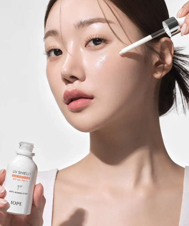 Femme appliquant IOPE UV Sheild Sun Ampoule SPF 50+PA+++ 40ml sur sa peau, protection solaire et soin du visage.