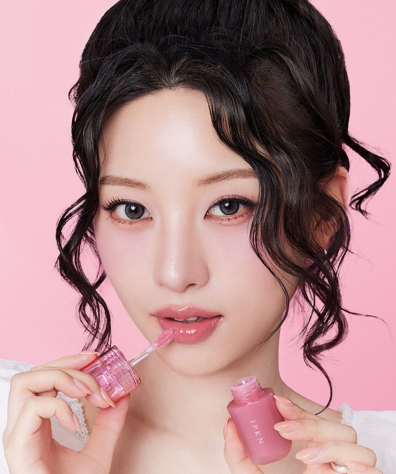 Portrait maquillage sur fond rose : IPKN Bubble Jam Gloss de la marque IPKN, flacons de gloss brillants en gros plan.