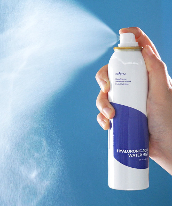 Main tenant ISNTREE Hyaluronic Acid Water Mist 100ml, brume hydratante sur fond bleu, produit de soins visage ISNTREE.