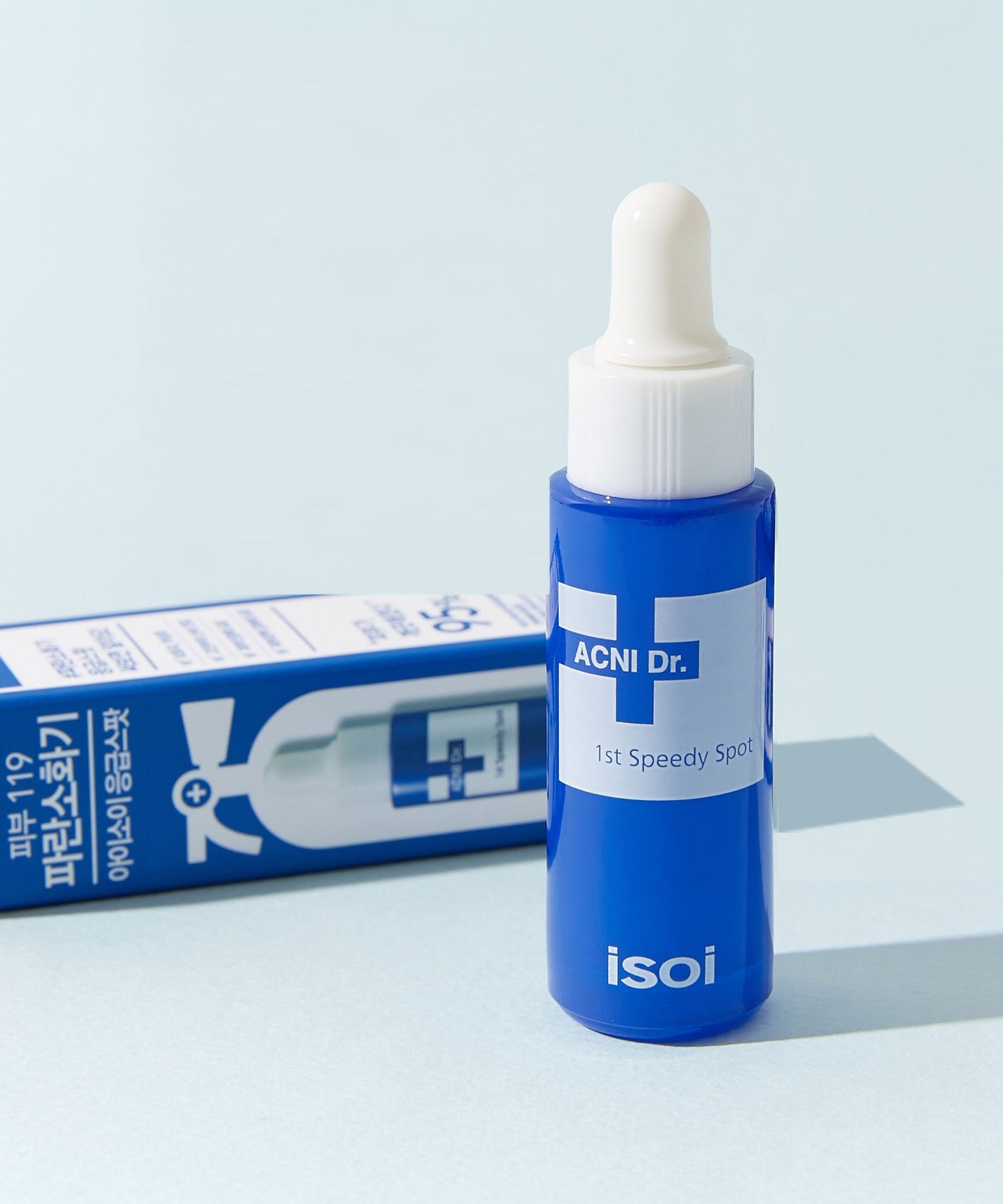 ISOI ACNI Dr. 1st Speedy Spot (14ml) de la marque ISOI, sérum anti-imperfections sur fond bleu clair avec boîte
