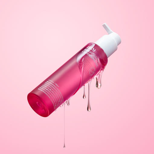 ISOI Brightening Cleansing Oil 150ml, flacon rose avec gouttes, sur fond rose en studio—brillance et nettoyage.