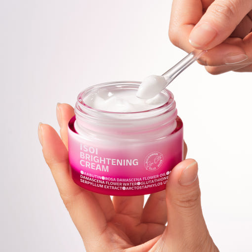 ISOI Brightening Cream 55ml : pot de crème blanche, main tenant l’onguent, texture sur cuillère, fond clair, marque ISOI.