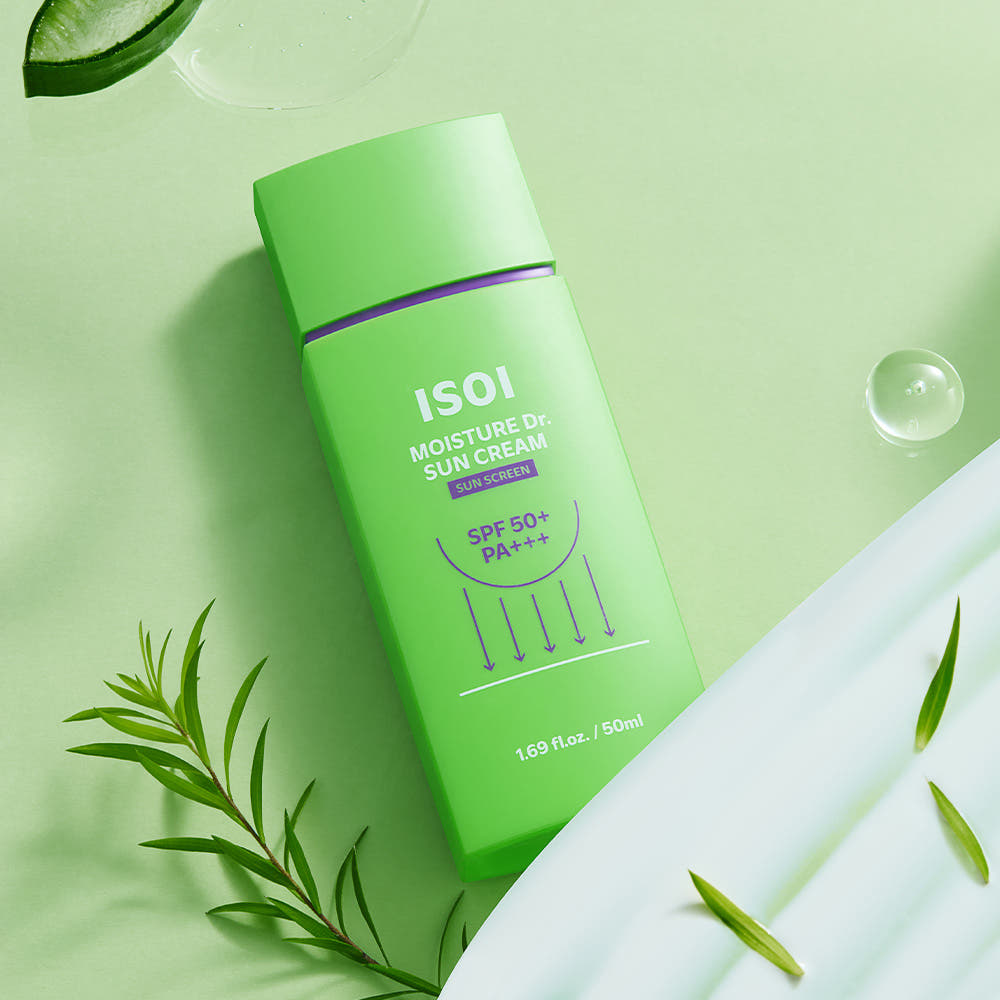 Décris l'image en français : ISOI Moisture Doctor Sun Cream SPF50+PA+++ 50ml, bouteille verte sur fond vert avec feuilles.