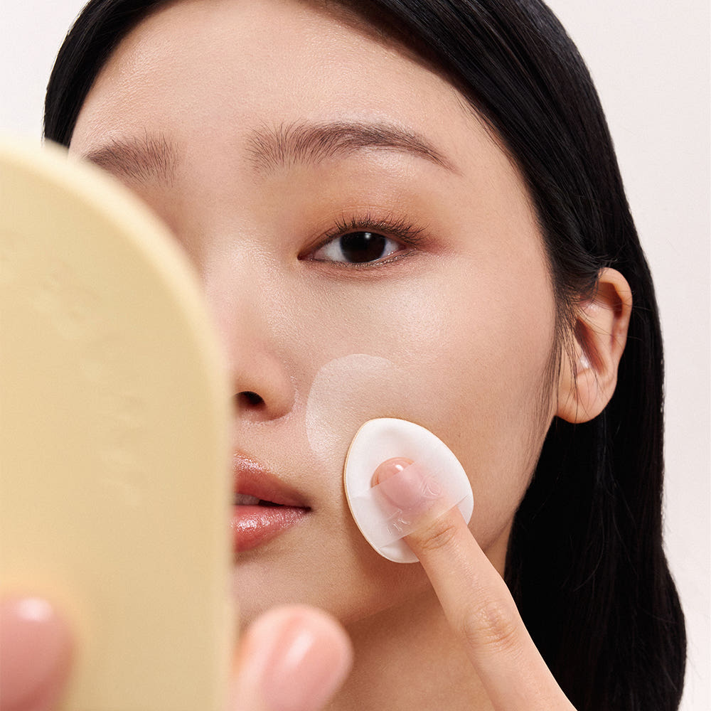 JAVINDESEOUL Wink Cushion Shade Primer 8g : la marque applique une crème sur le visage, texture crème illuminatrice.