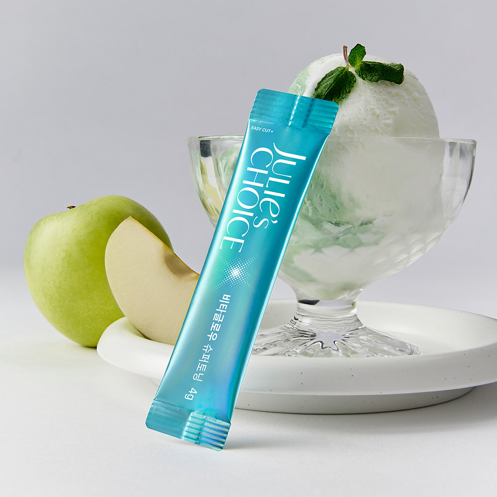 Décris l’image en français : JULIE'S CHOICE Vita Glow Super Toning de la marque, tube bleu sur fond blanc, pomme verte.