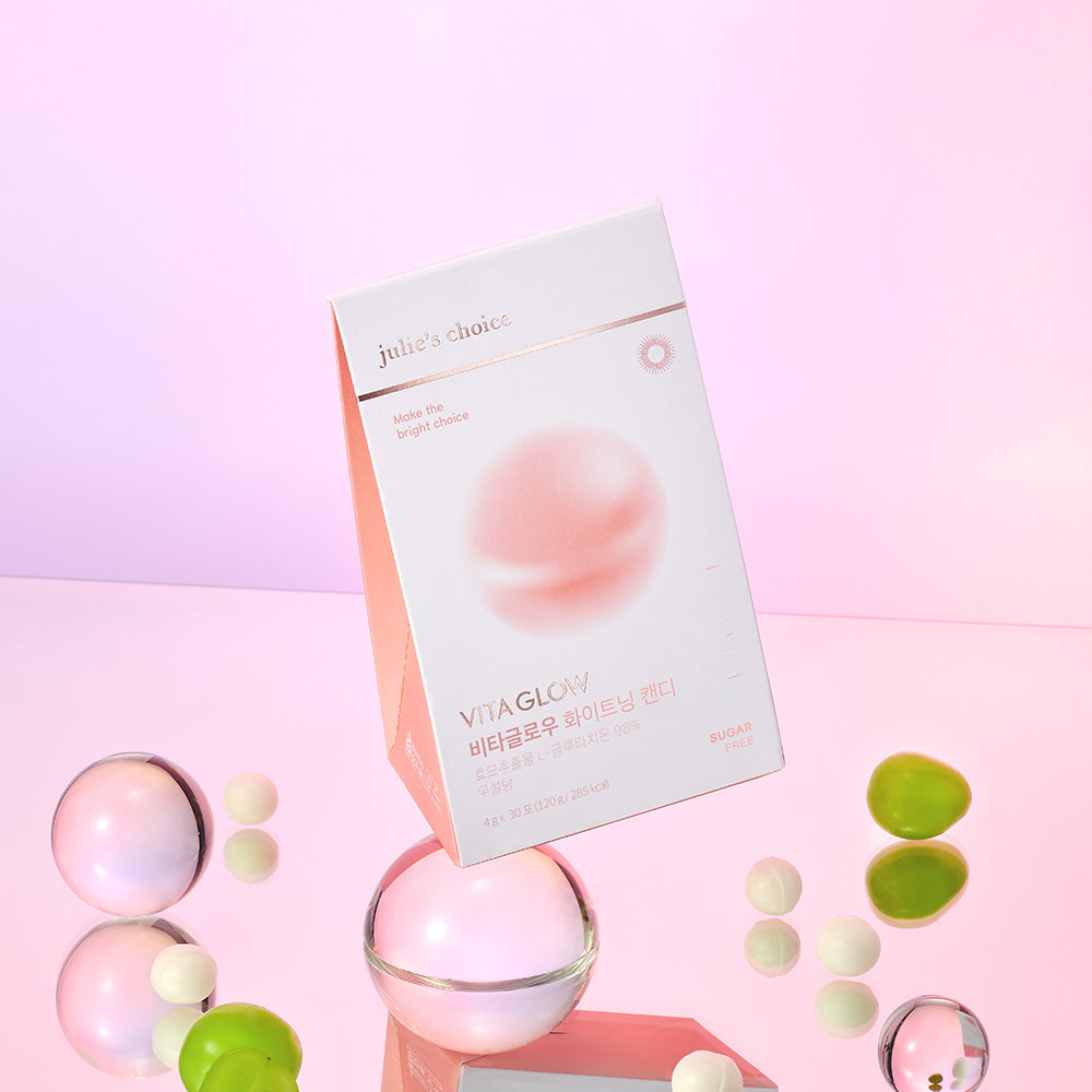 JULIE'S CHOICE Vita Glow Whitening Candy, boite et bonbons sur fond rose pastel, marque visible, décor cosmétique.