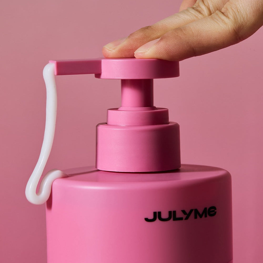 Main ouvre JULYME Damage Care Perfume Hair Treatment 500ml, bouteille rose JULYME sur fond rose, soins capillaires