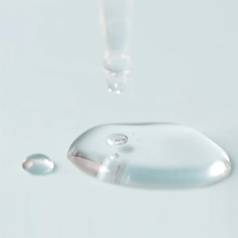 Décris l'image en français en mentionnant le produit, la marque et le contexte visuel : JUMISO D-Panthenol Barrier Soothing Serum 70ml, gouttelette sur flacon bleu pâle.