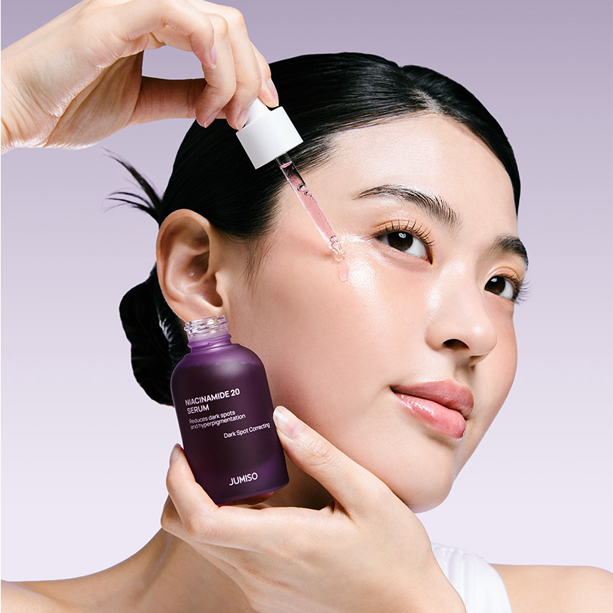 JUMISO Niacinamide 20 Serum 40ml en application sur le visage, main tenant le flacon, contexte beauté en studio