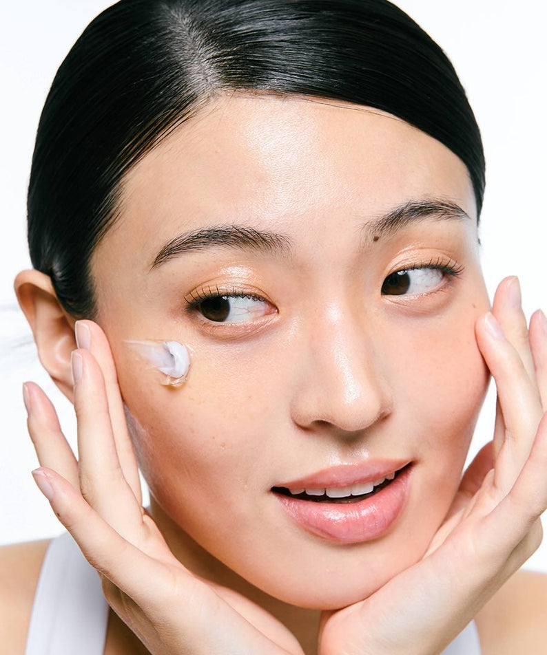 Décrivez l'image en français : JUMISO  Niacinamide 5 Plus Overnight Cream 80ml, femme applique la crème sur le visage, studio blanc.