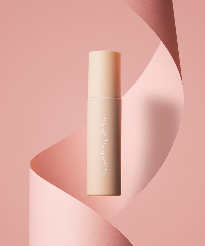 KAHI One Layer Tone-up Body Mist 100ml : flacon sur fond rose abstrait, marque KAHI en contexte maquillage beauté.