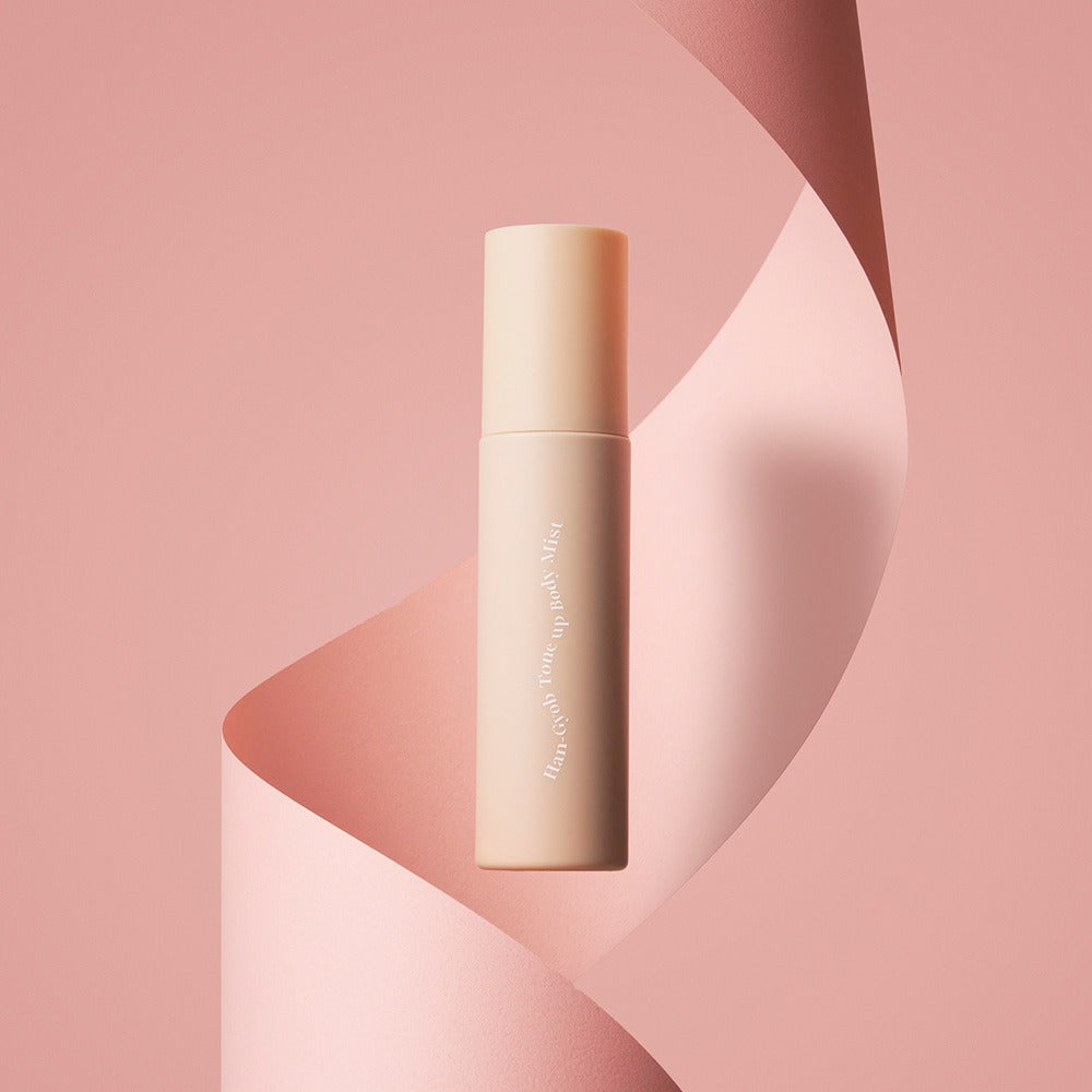 KAHI One Layer Tone-up Body Mist 100ml : flacon sur fond rose abstrait, marque KAHI en contexte maquillage beauté.