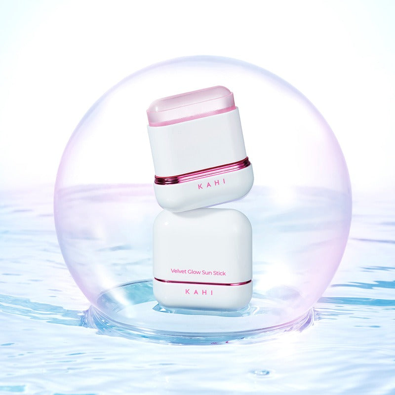 KAHI Velvet Glow Sun Stick 13.5g de KAHI, packaging rose/blanc sur fond ciel et gouttes d’eau, ambiance spa