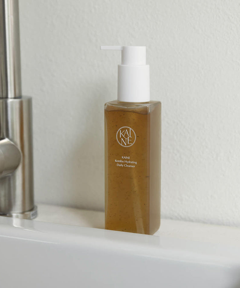 Flacon de 155g du KAINE Kombu Hydrating Daily Cleanser sur un évier dans une salle de bain moderne.