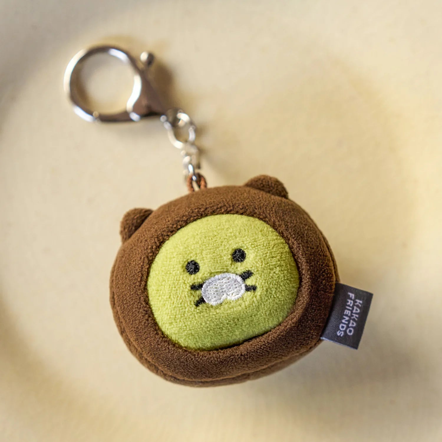KAKAO FRIENDS Dujjonchun keychain doll en peluche marron, sur fond clair, porte-clés avec anneau argenté.