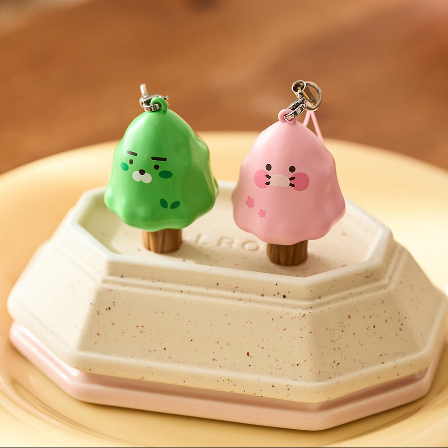KAKAO FRIENDS Peekaboo Moving Keyring, deux porte-clés mignons animés posés sur une boîte blanche, fond beige.