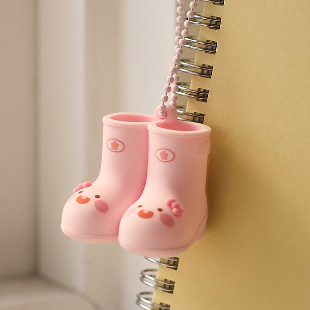 KAKAO FRIENDS Rain Boots Keychain : porte-clés bottes pluie roses, détail mignon sur un anneau, fond beige.