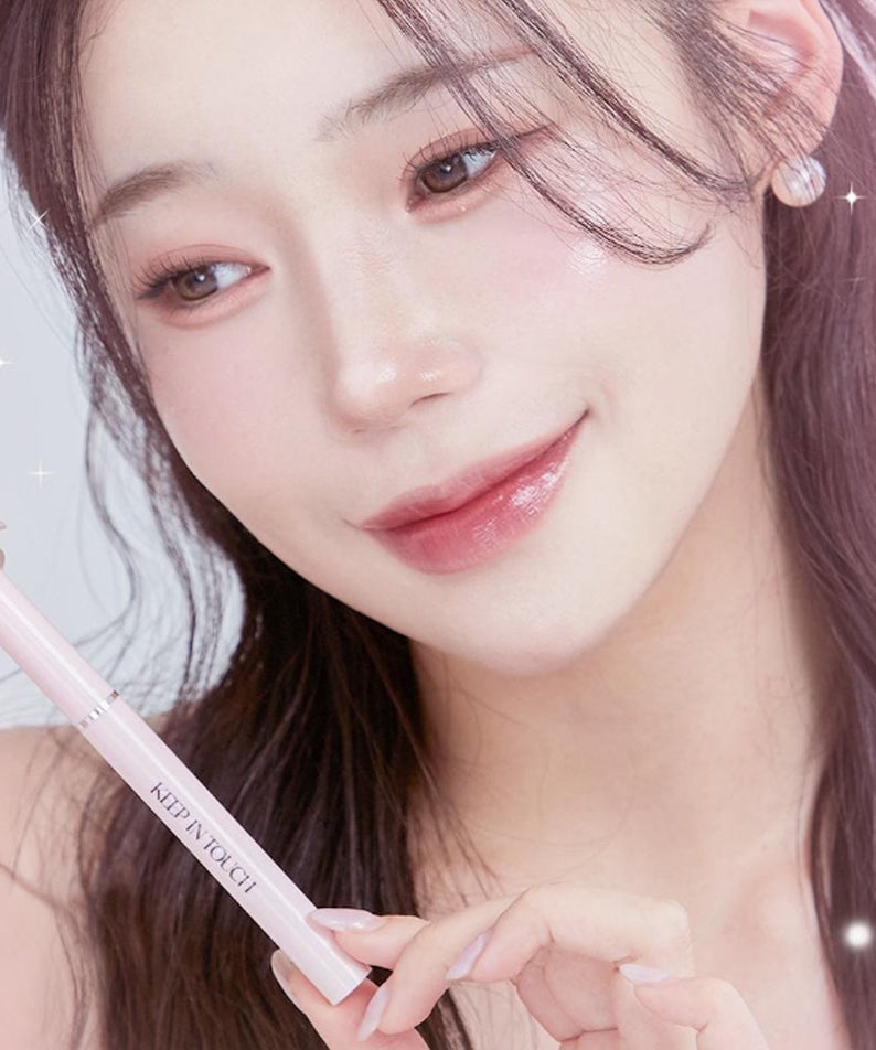 Femme souriante tenant le KEEP IN TOUCH Glow Lip Sealer Pencil pour un look éclatant et naturel.