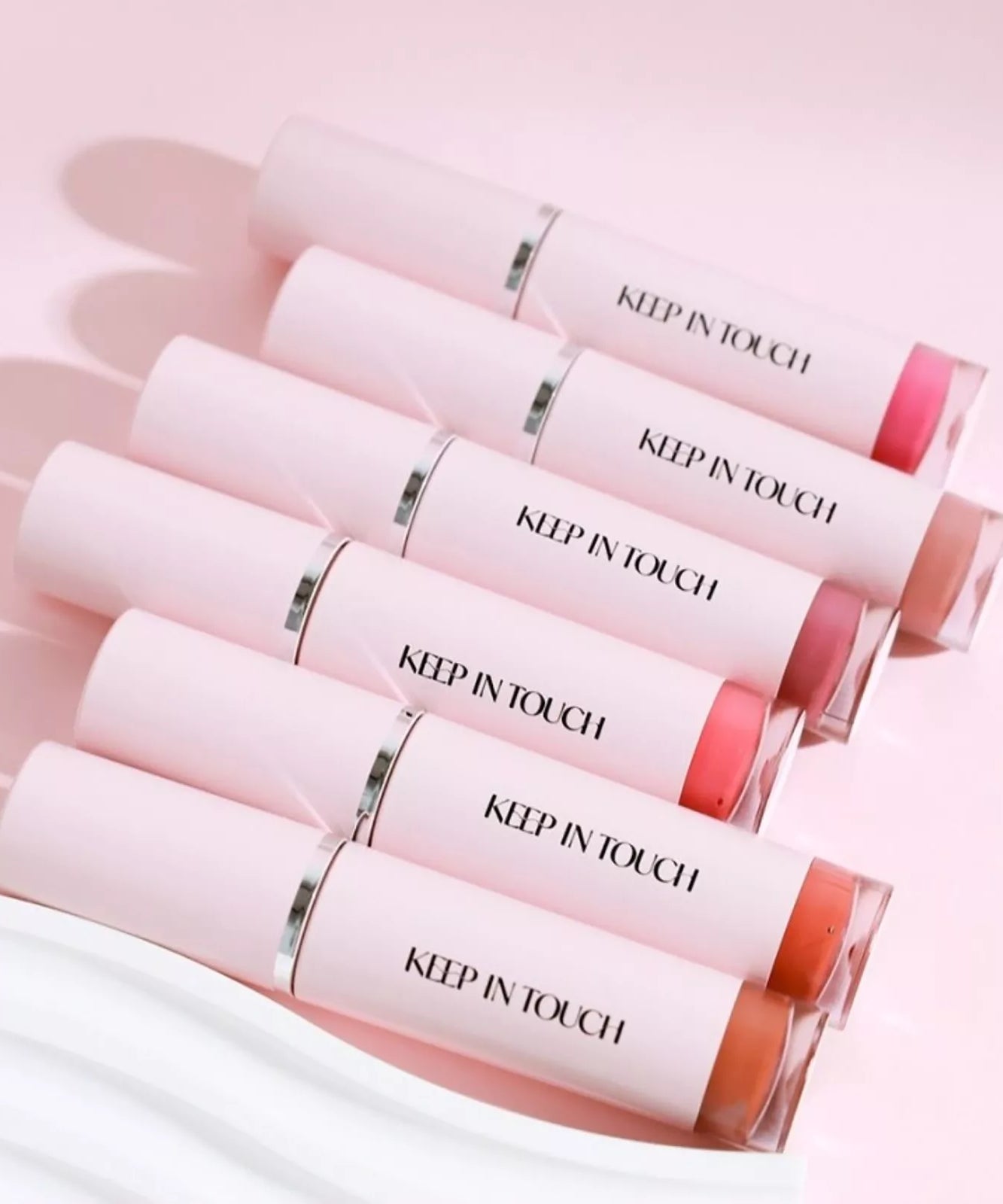 KEEP IN TOUCH Glow Water Lip Tint en différentes teintes sur fond rose élégante.