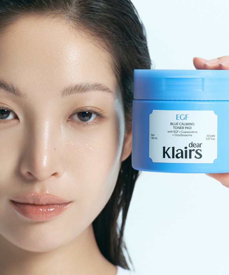 Décris l'image en français : KLAIRS EGF Blue Calming Toner Pads 60 Pads, pot bleu EGF, visage apaisé, marque KLAIRS