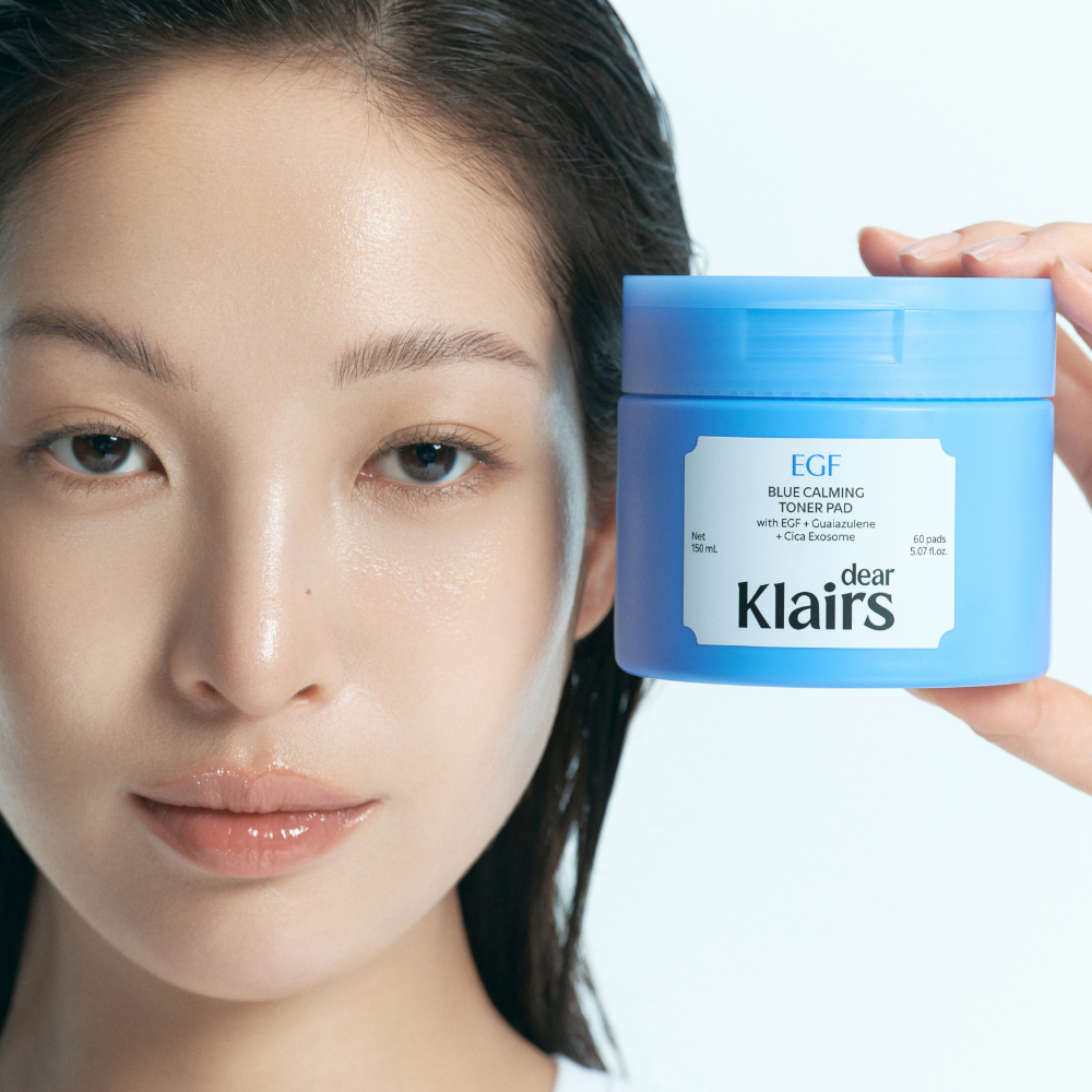 Décris l'image en français : KLAIRS EGF Blue Calming Toner Pads 60 Pads, pot bleu EGF, visage apaisé, marque KLAIRS