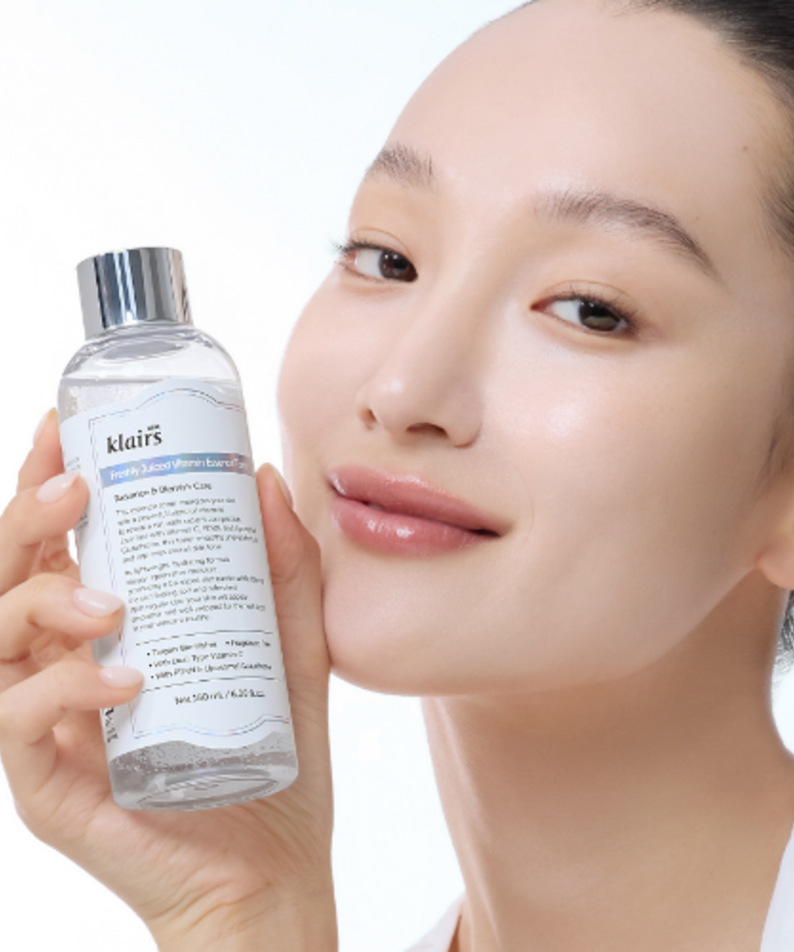 Femme souriante tenant KLAIRS Freshly Juiced Vitamin Blemish Toner 180ml, produit pour une peau éclatante.