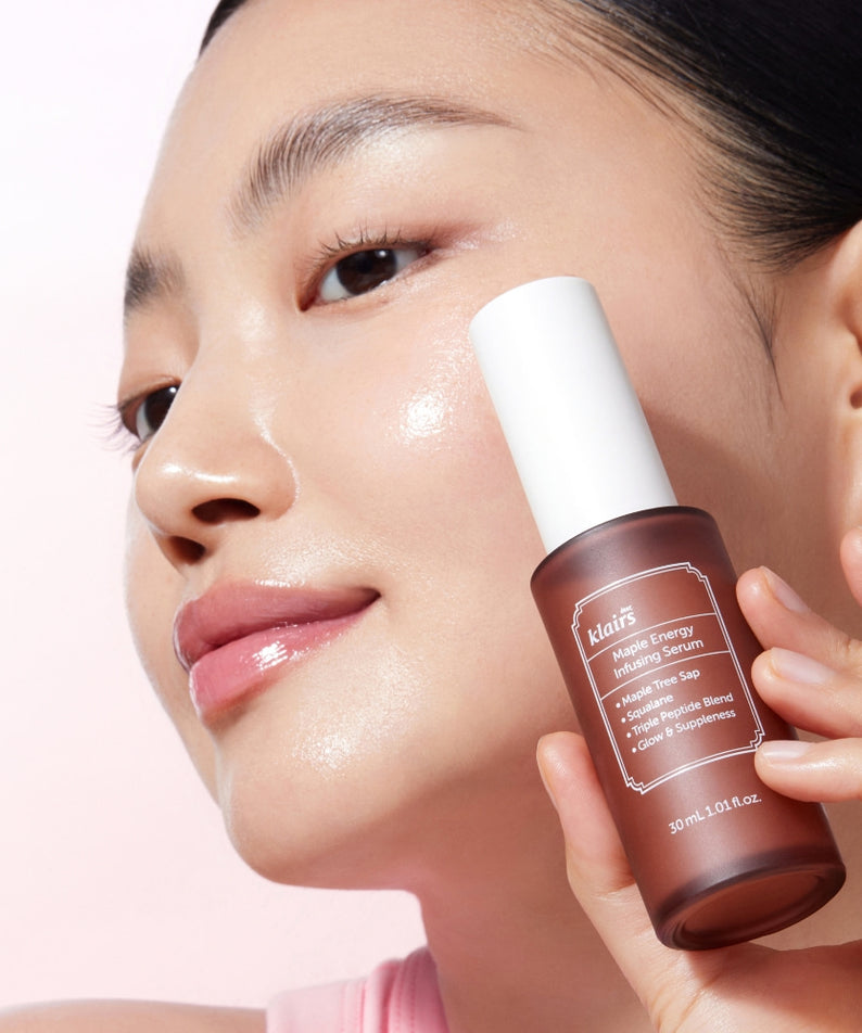 Femme souriante avec sérum KLAIRS Maple Energy Infusing Serum 30ml sur fond rose, soulignant l'efficacité du produit.