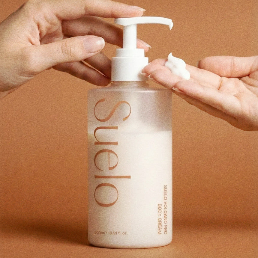SUELO Volcano Body Slimming Anti-Puffiness Cream 500ml : pompe dose, mains appliquant la crème sur peau, bouteille SUELO, visuel produit.