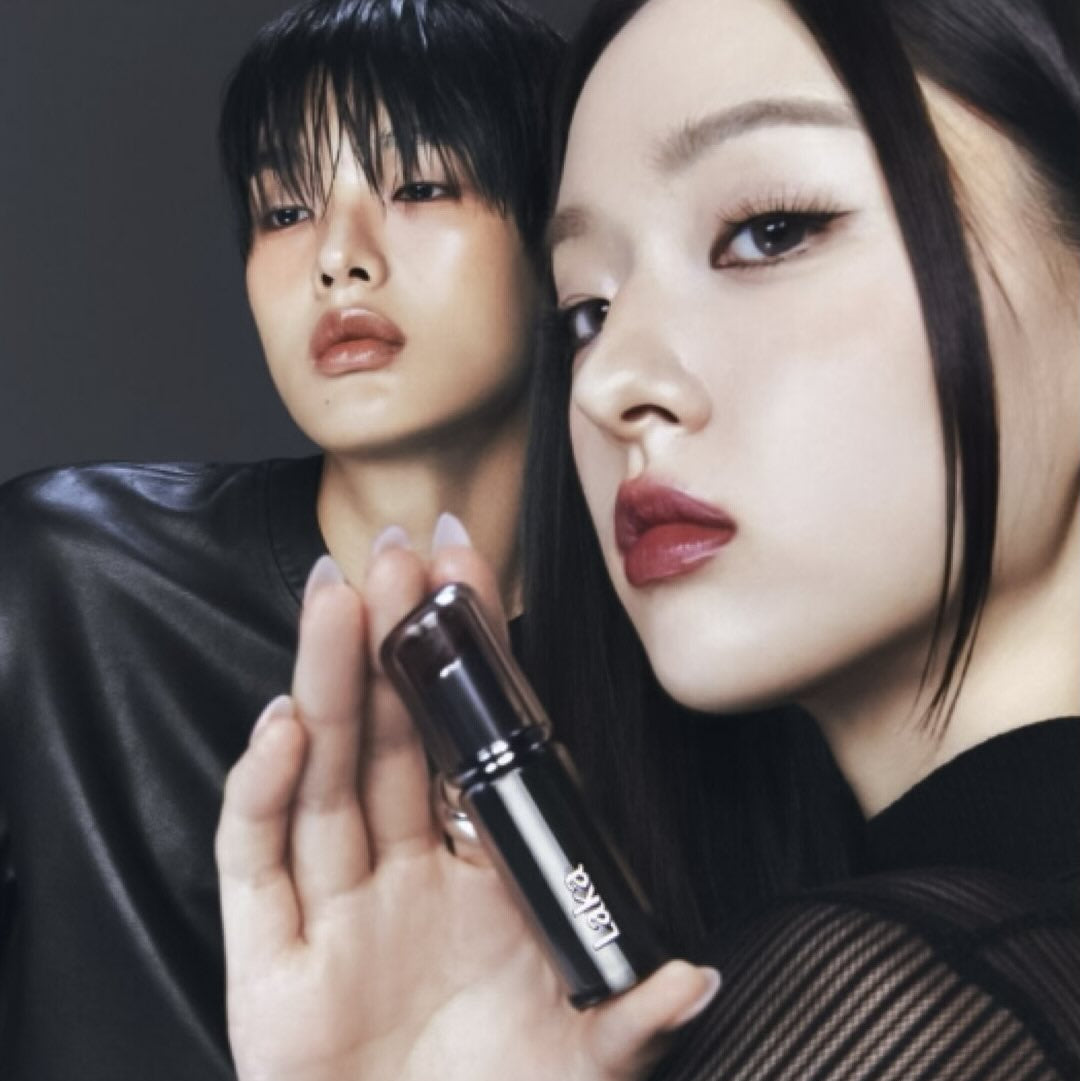 LAKA Devillip, maquillage par LAKA : deux modèles en studio tenant un rouge à lèvres, fond sombre, éclairage dramatique.