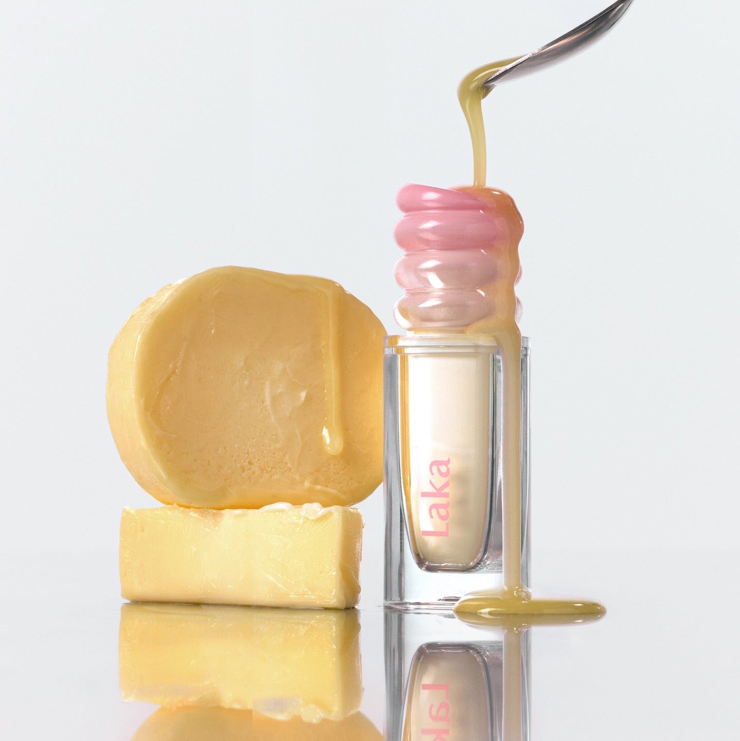 LAKA Maxi Glare Tint, marque LAKA : sérum brillant avec goutte dorée, flacons et savon, fond blanc.