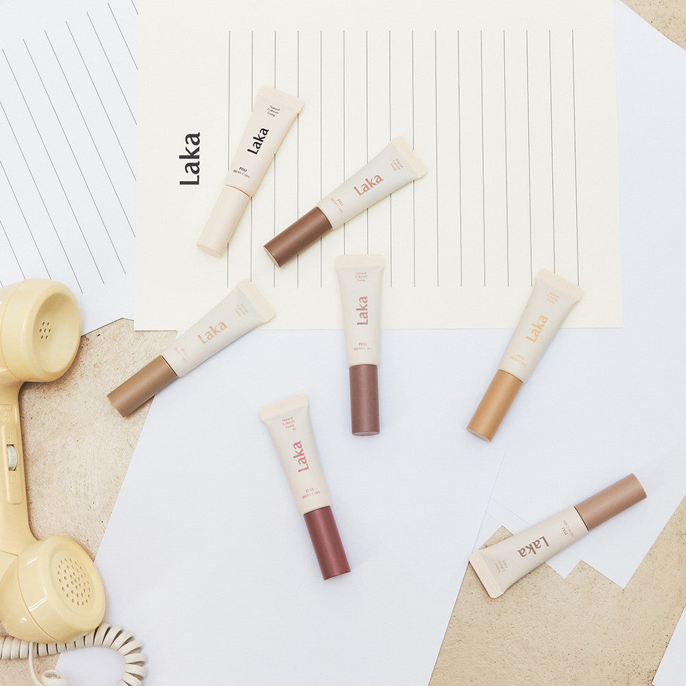 LAKA Pixi Brow Cara 8g, tubes de maquillage LAKA sur fond clair avec textures, accessoires et lumière naturelle.