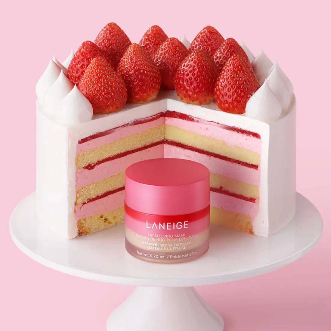 Décris l'image en français : LANEIGE Lip Sleeping Mask EX Strawberry Shortcake 20g, pot rose sur gâteau aux fraises.