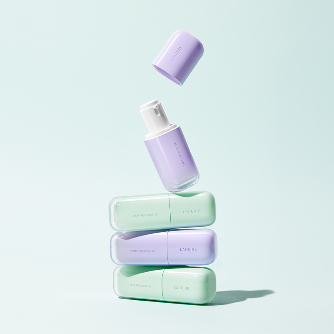 Décris l'image en français : LANEIGE Skin Veil Base SPF28/PA++ 30ml, base visage de la marque LANEIGE, flacons pastel sur fond bleu.
