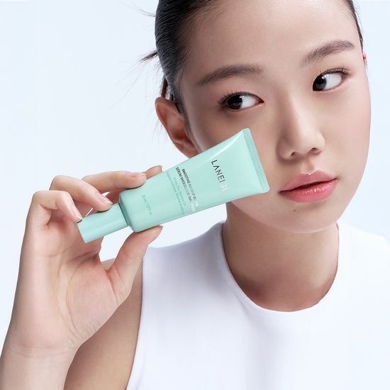 Décris l'image en français : LANEIGE Smoothie Makeup Serum 30ml de la marque LANEIGE, maquillage, tube menthe sur modèle
