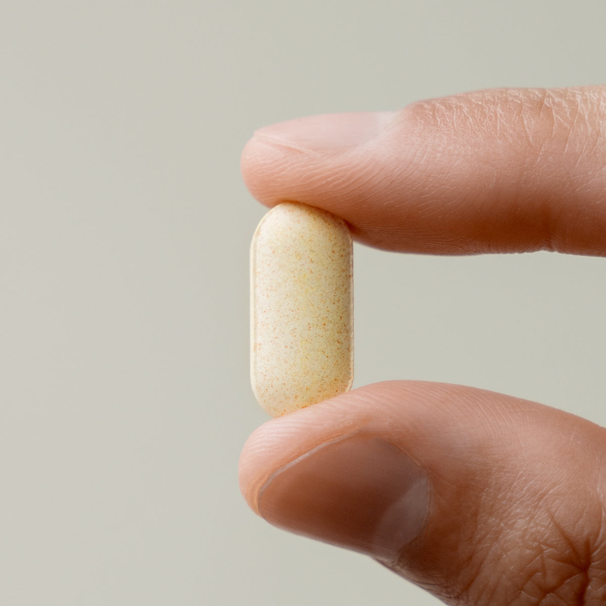 LAZY SOCIETY 1 Black + Multivitamin Set, capsule montrée entre deux doigts, marque LAZY SOCIETY, fond clair.