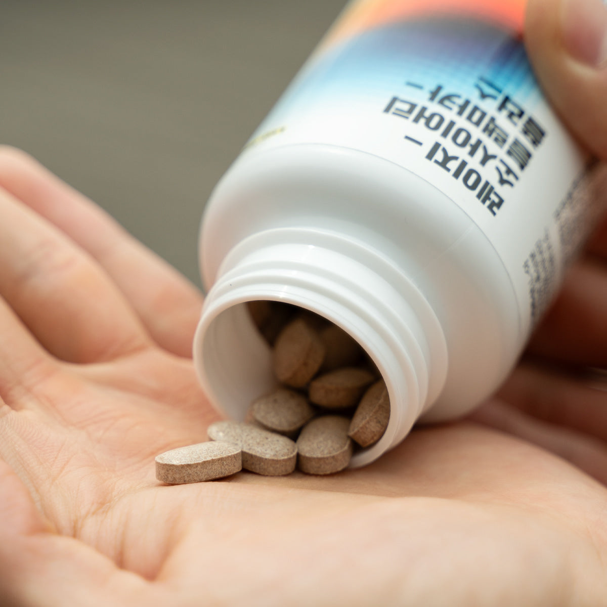 LAZY SOCIETY 1 Black + Multivitamin Set : mains tenant un flacon blanc de comprimés, style photo produit.