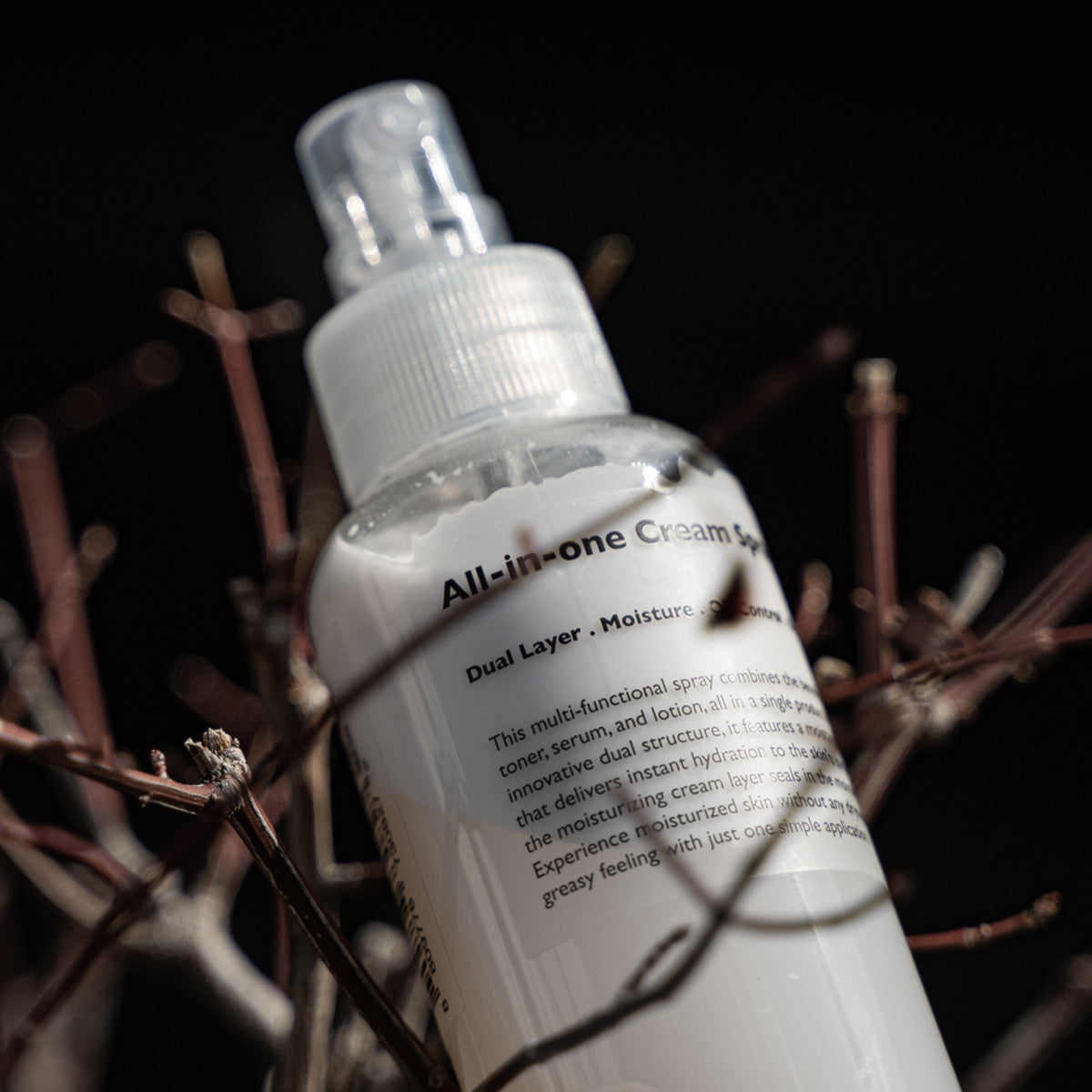 LAZY SOCIETY All-in-One Cream Spray 120ml, spray crème en gros plan sur tiges, style photo studio sombre