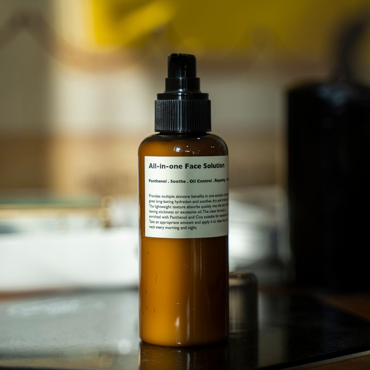 LAZY SOCIETY All-in-One Face Solution 150g, flacon brun à pompe sur table, arrière-plan flou, salle de bain.