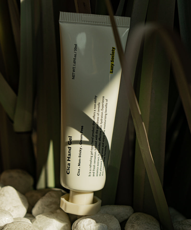 LAZY SOCIETY Cica Hand Gel 50ml, tube sur galets et herbes, ambiance naturelle, marque visible en contexte spa